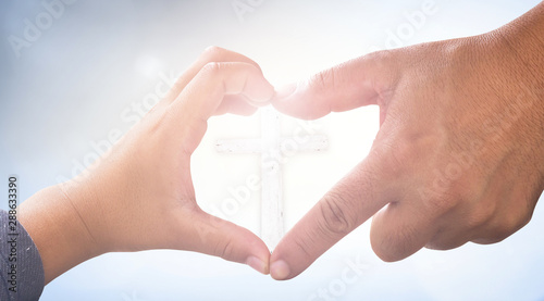 Love Jesus concept: Heart shape of father and son hands with cross photo