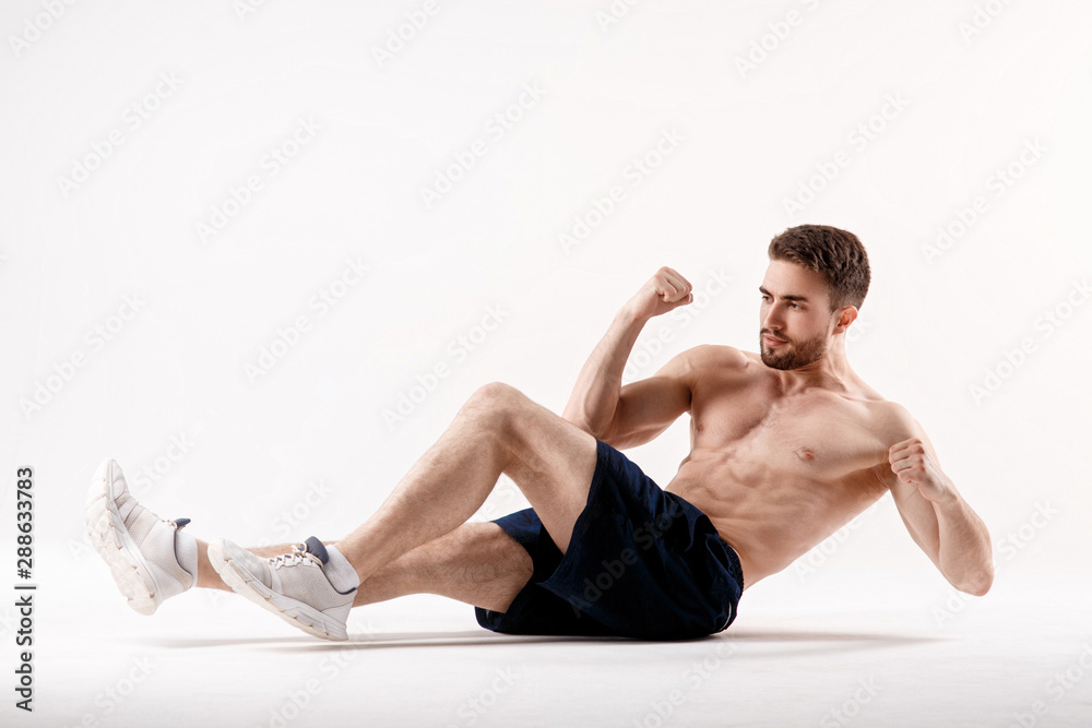 young man with a beard of a sports physique does an exercise on the muscles of the abdominal cavity on a white isolated background, the athlete goes in for sports, exercise on the muscles of the press young man with a beard of a sports physique does an exercise on the muscles of the abdominal cavity on a white isolated background, the athlete goes in for sports, exercise on the muscles of the press