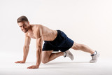 young man with a beard of a sports physique does an exercise on the muscles of the abdominal cavity on a white isolated background, the athlete goes in for sports, exercise on the muscles of the press