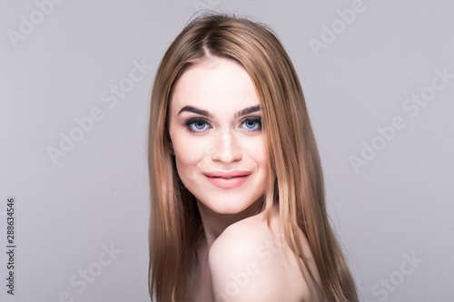 Beauty portrait of a happy woman with fresh skin and eyes closed looking at camera on a white background