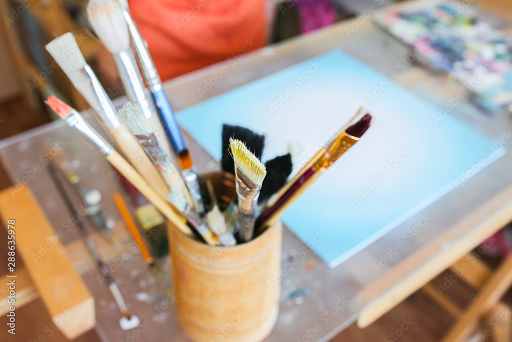 Fototapeta premium Real work studio of the painter. Man is creating picture. Artist concept. Creative atmosphere. Paint brushes.