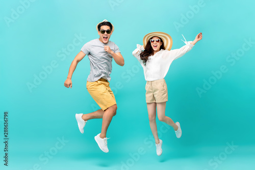 Energetic Asian couple in summer beach casual clothes jumping