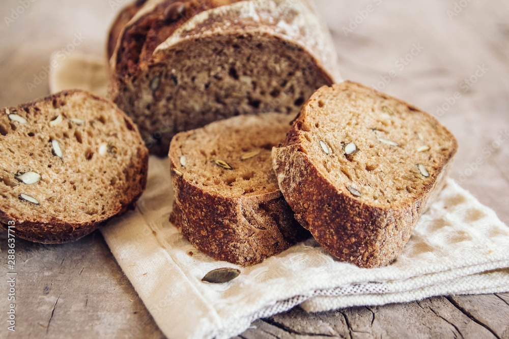 Brown fresh bread with seeds are cut into pieces on old wood background. Top view, copy space Brown fresh bread with seeds are cut into pieces on old wood background. Top view, copy space