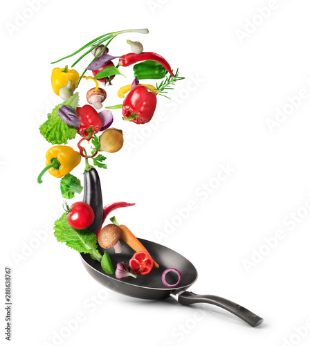 Cooking concept. Vegetables are flying out of the pan isolated on white background. Healthy food. photo