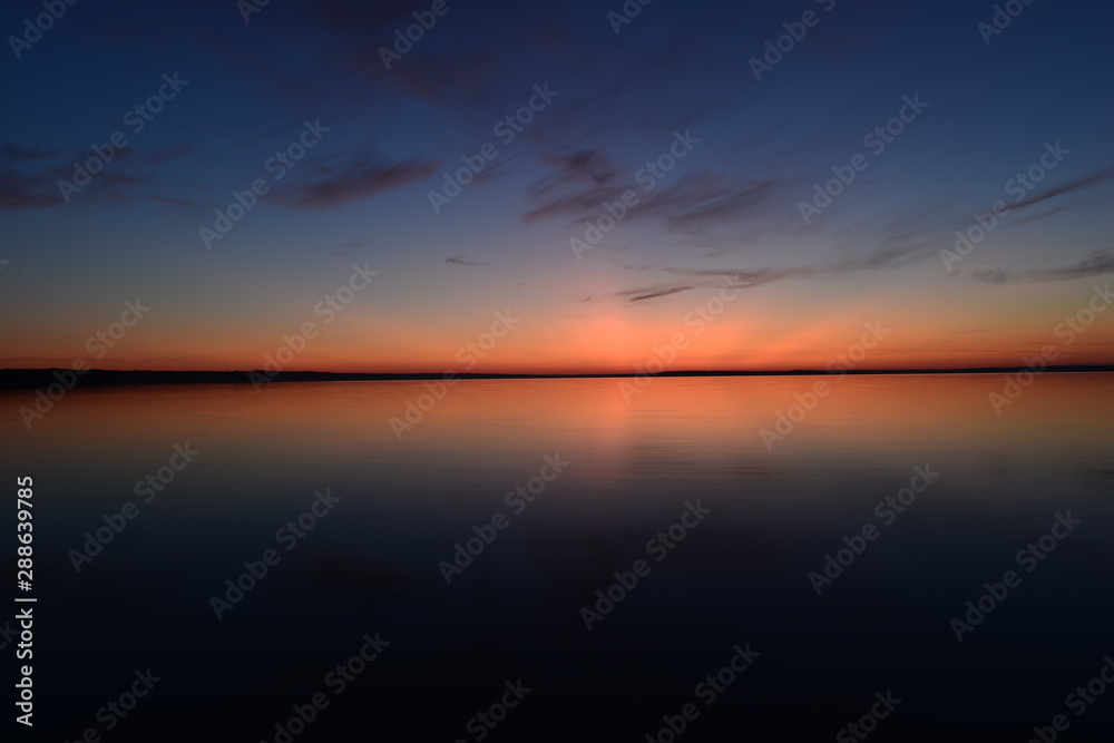 Blue sky in a bright twilight glow in calmness on the horizon above  water