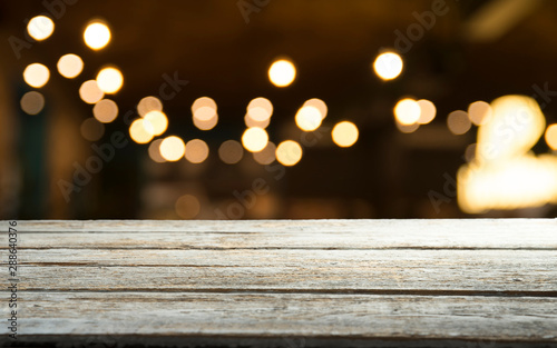 Empty wood table top on blur light gold bokeh of cafe restaurant in dark background © kishivan