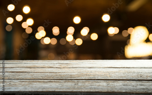 Empty wood table top on blur light gold bokeh of cafe restaurant in dark background