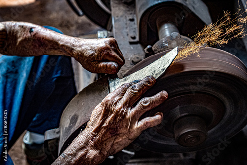 Hands of craftsman making sickle photo