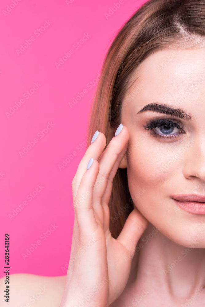 Young female touches her face over pink background, copyspace Young female touches her face over pink background, copyspace