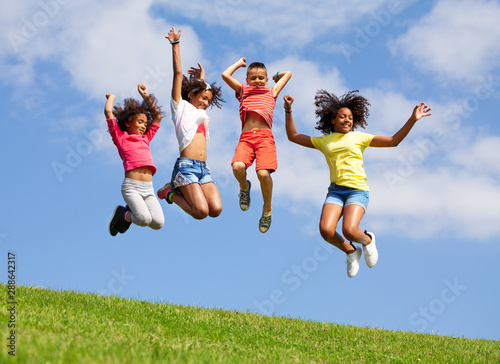 Group four jumping kids over blue sky