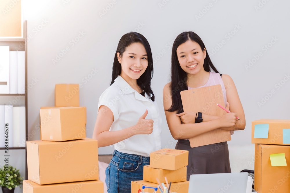 Asian beautiful empower woman and friend working with online business shop at home.Owner businesswoman start up with Accept orders,Check number of products,Prepare to deliver products to customers. Asian beautiful empower woman and friend working with online business shop at home.Owner businesswoman start up with Accept orders,Check number of products,Prepare to deliver products to customers.