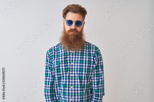 Young redhead irish man wearing casual shirt and sunglasses over isolated white background depressed and worry for distress, crying angry and afraid. Sad expression.