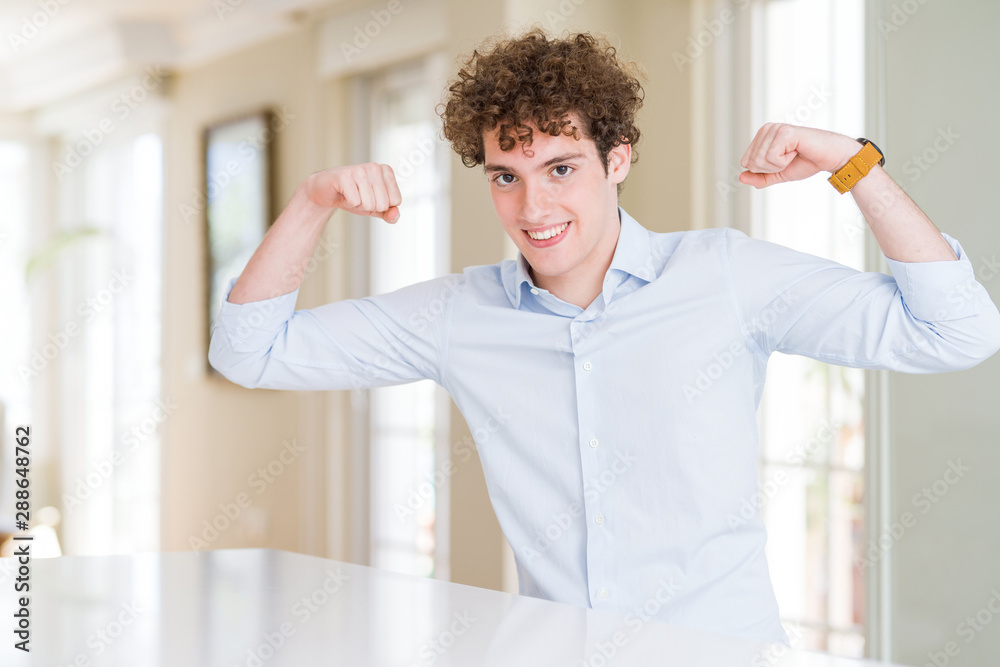 Young business man with curly read head showing arms muscles smiling proud. Fitness concept. Young business man with curly read head showing arms muscles smiling proud. Fitness concept.