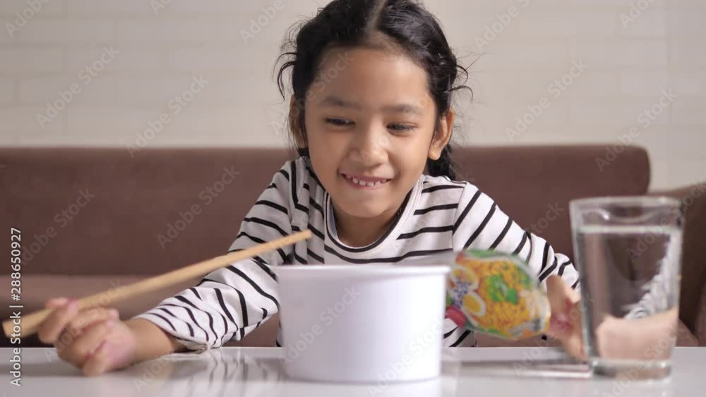 Asian little girl using chopstick to eat delicious instant noodle with happiness select focus shallow depth of field Asian little girl using chopstick to eat delicious instant noodle with happiness select focus shallow depth of field