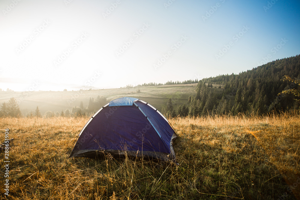 Morning landscape in mountains with tent. Camp rest in autumn forest