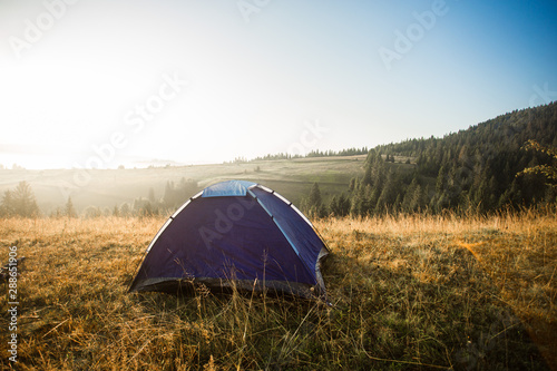 Morning landscape in mountains with tent. Camp rest in autumn forest