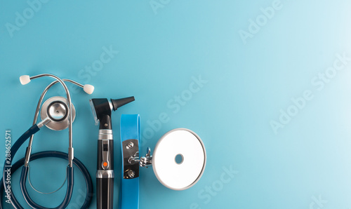 Otoscope with stethoscope and reflector mirror on blue background. photo