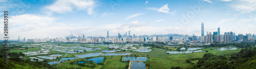 panorama view of rural green fields with fish ponds between Hong Kong and skylines of Shenzhen,China