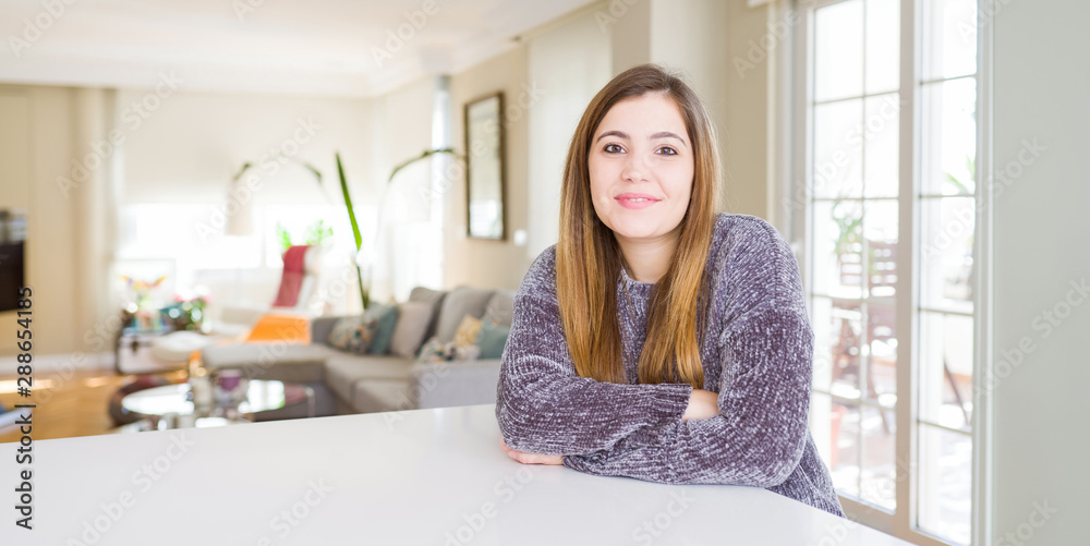 Beautiful young woman at home happy face smiling with crossed arms looking at the camera. Positive person.