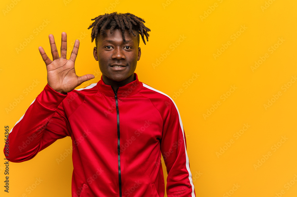 Young fitness black man smiling cheerful showing number five with fingers. Young fitness black man smiling cheerful showing number five with fingers.