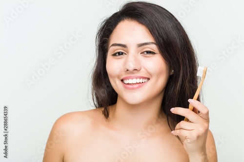 Close up of a young beautiful and natural hispanic woman holding a toothbrush