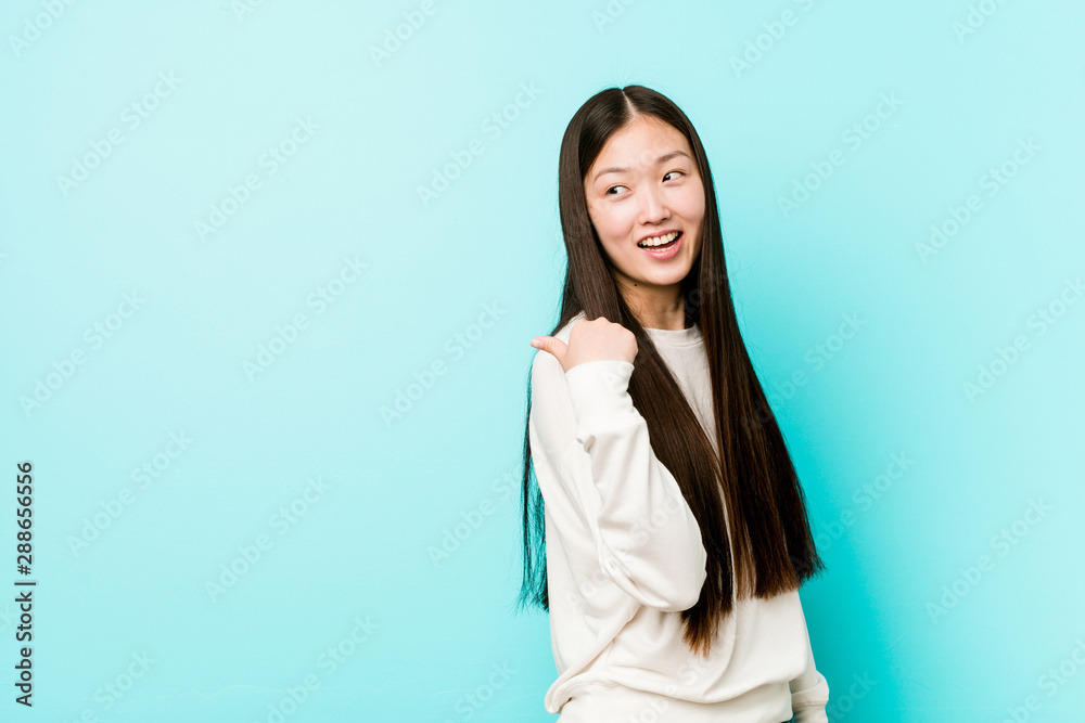 Young pretty chinese woman points with thumb finger away, laughing and carefree. Young pretty chinese woman points with thumb finger away, laughing and carefree.