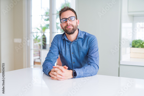 Handsome man wearing glasses and smiling relaxed at camera © Krakenimages.com