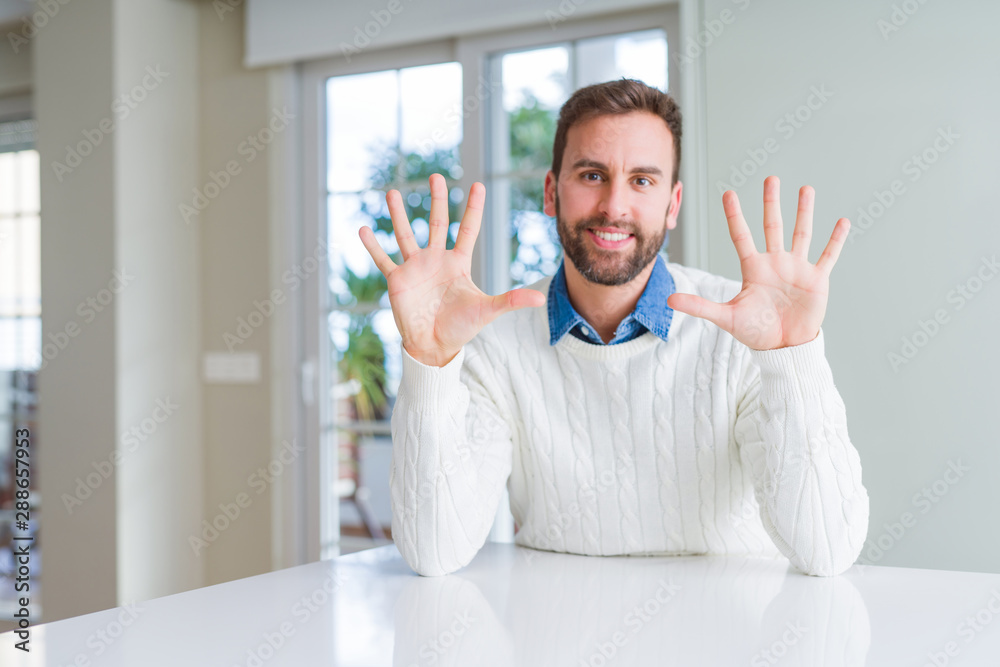 Handsome man wearing casual sweater showing and pointing up with fingers number ten while smiling confident and happy. Handsome man wearing casual sweater showing and pointing up with fingers number ten while smiling confident and happy.