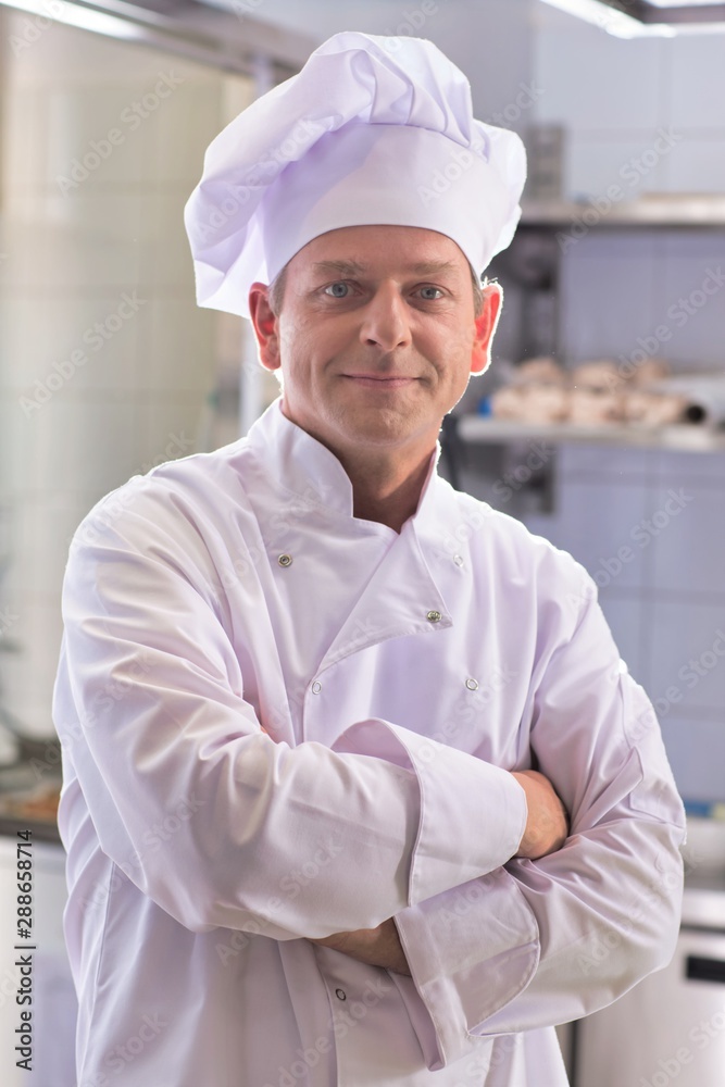 Portrait of confident mature chef standing with arms crossed in kitchen at restaurant