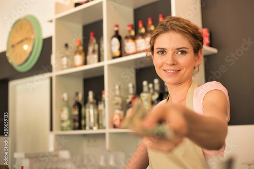 Portrait of smiling young waitress giving customer change while standing at counter in restaurant