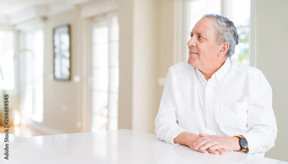 Handsome senior man at home looking away to side with smile on face, natural expression. Laughing confident. Handsome senior man at home looking away to side with smile on face, natural expression. Laughing confident.