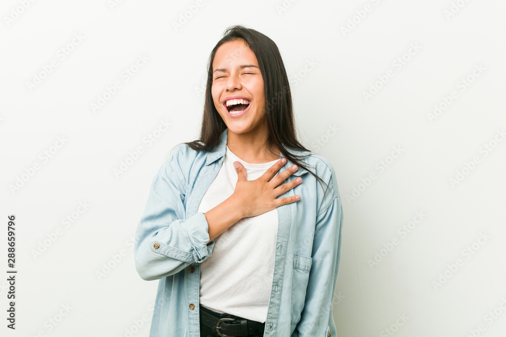 Young hispanic woman laughs out loudly keeping hand on chest. Young hispanic woman laughs out loudly keeping hand on chest.