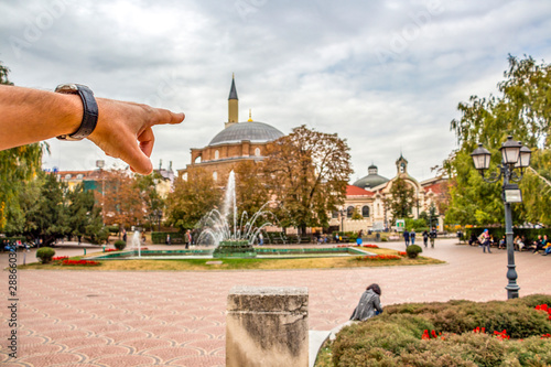 Male hand pointing at the blurred Banski Square with Banya Bashi Mosque, famous touristic place in Sofia downtown, Bulgaria photo