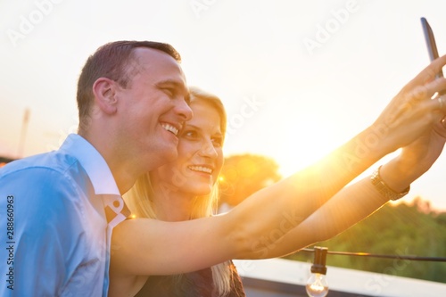Smiling businesswoman taking selfie with colleagues during rooftop party