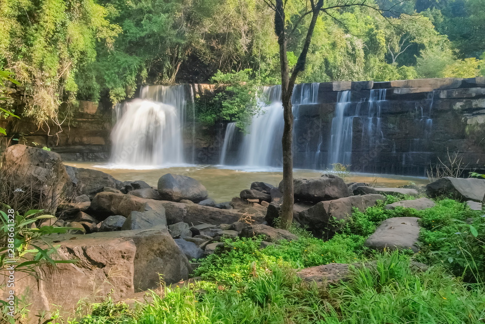 Obraz premium view of waterfall flowing around with arch rocks and green forest background, Sridit Waterfall, Khao Kho, Phetchabun, thailand.