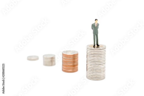 Miniature businessman standing on stack of new Thai Baht coins, isolated on white background. Business and finance concept.