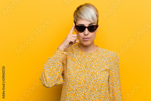 Valokuva Young curvy woman wearing a floral summer clothes pointing temple with finger, thinking, focused on a task