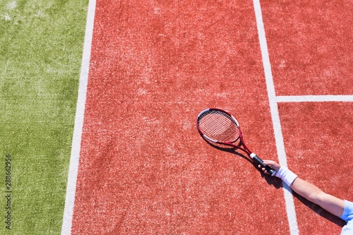 Disappointed mature man lying while holding tennis racket on court during summer