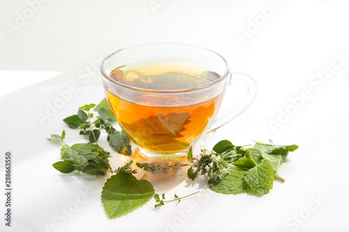 cup of hot herbal tea with mint, lemon balm and oregano flowers