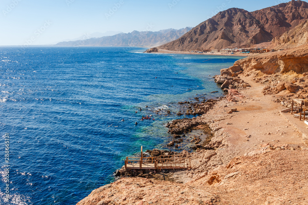 Sunny resort beach at the coast shore of Red Sea in Dahab, Sinai, Egypt, Asia in summer hot. Famous tourist destination Blue Hole near of Sharm el Sheikh. Bright sunny light