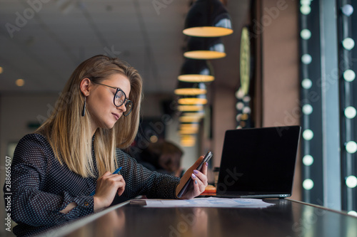 Young business lady communicates on social networks on the phone in between work