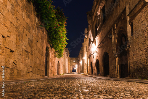 Night photo of ancient street of the Knights in Rhodes city on Rhodes island  Dodecanese  Greece. Stone walls and bright night lights. Famous tourist destination in South Europe