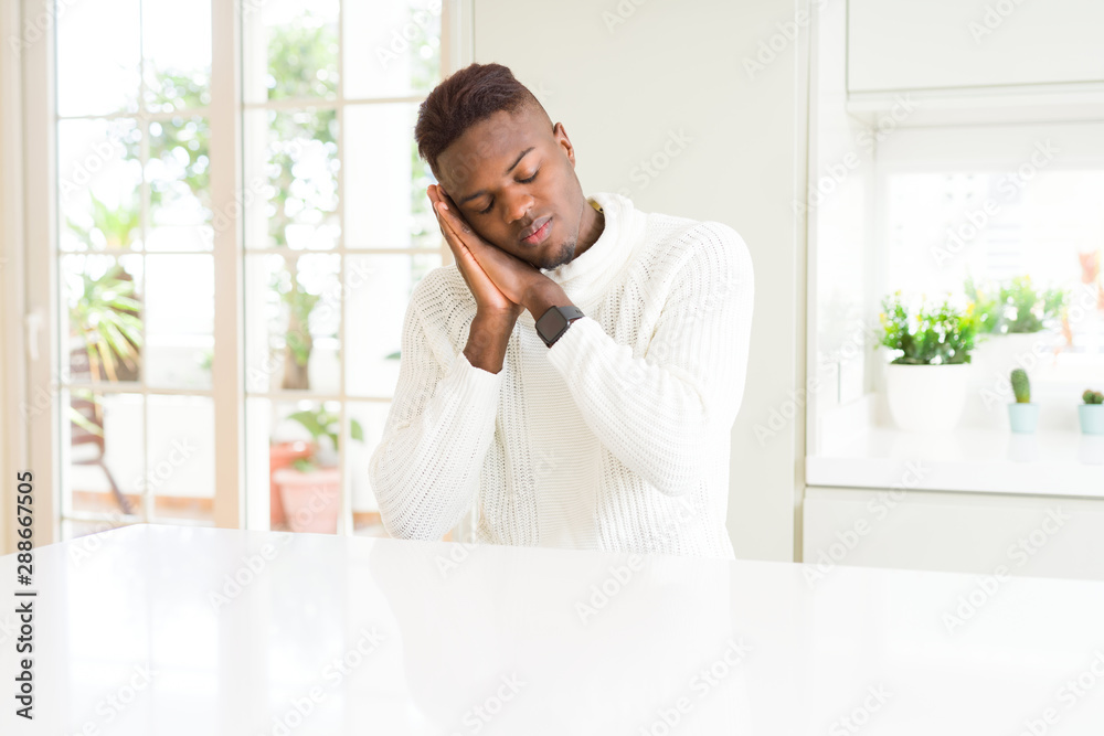Handsome african american man on white table sleeping tired dreaming and posing with hands together while smiling with closed eyes. Handsome african american man on white table sleeping tired dreaming and posing with hands together while smiling with closed eyes.