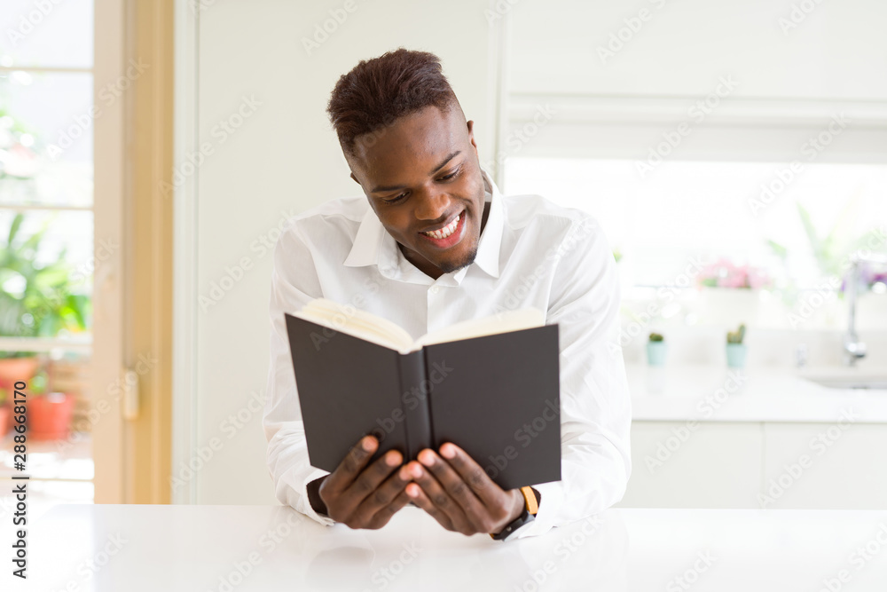 Young african man reading a book, studying for univeristy smiling confident Young african man reading a book, studying for univeristy smiling confident