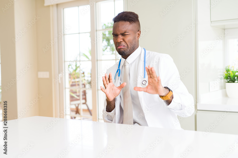 African american doctor man at the clinic disgusted expression, displeased and fearful doing disgust face because aversion reaction. With hands raised. Annoying concept. African american doctor man at the clinic disgusted expression, displeased and fearful doing disgust face because aversion reaction. With hands raised. Annoying concept.