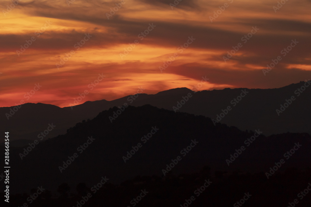 Fototapeta premium Dark yellow clouded sky with black mountains