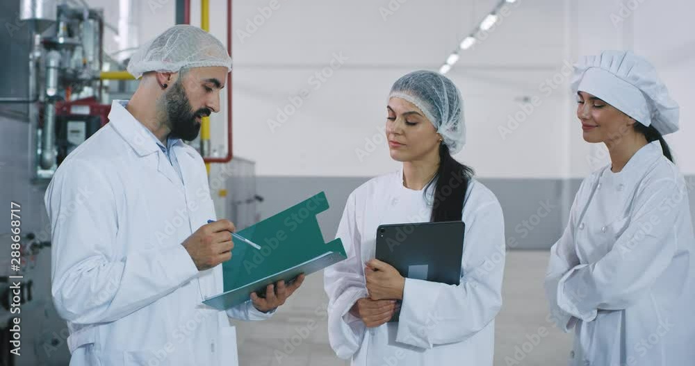 Meeting time between engineer and bakery workers in the big manufacturing engineer explaining the security notes about the industrial machine Meeting time between engineer and bakery workers in the big manufacturing engineer explaining the security notes about the industrial machine