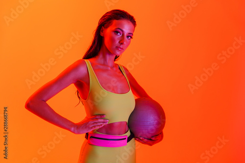 Photo of pretty brunette woman wearing formfitting sportswear holding gymnastic ball while doing workout photo