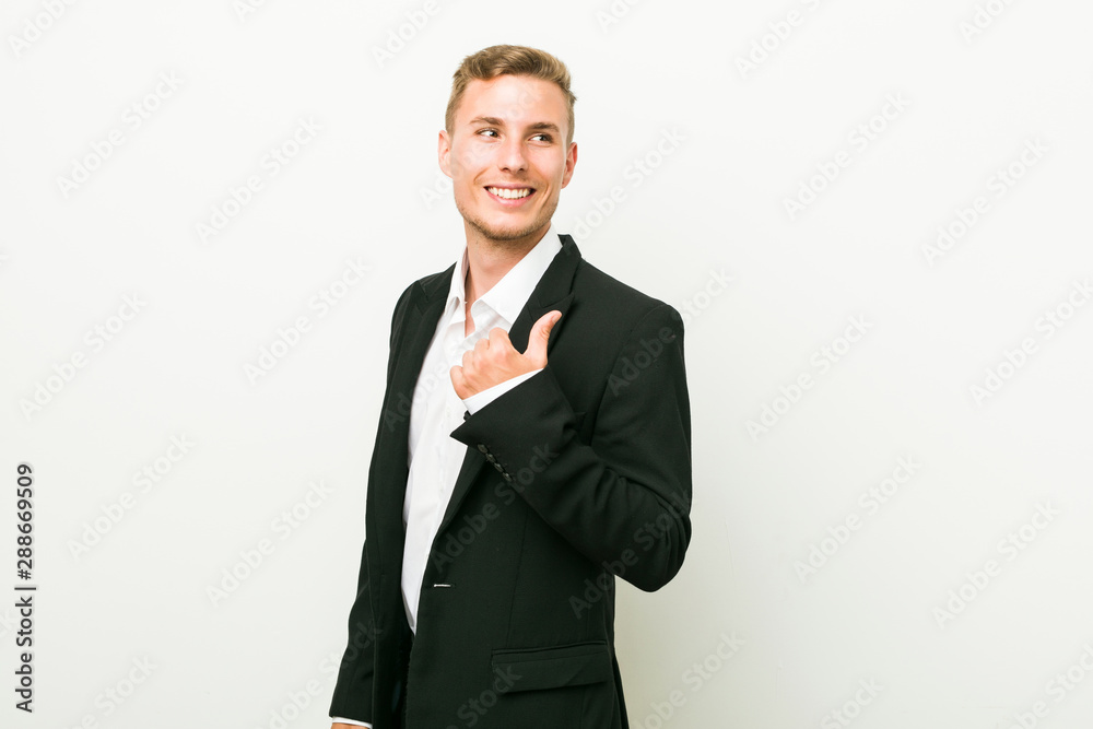 Young caucasian business man points with thumb finger away, laughing and carefree. Young caucasian business man points with thumb finger away, laughing and carefree.