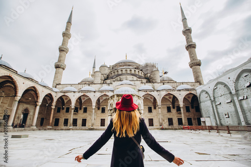 Photography Young woman traveler in hat and black coat looking at the blue mosque in Istanbul, Turkey